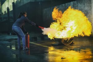 Woman putting out a lithium-ion battery fire with an extinguisher.