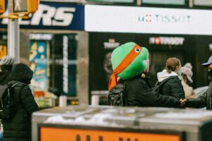 Someone dressed in a Ninja Turtle costume conversates with a passerby on the street.